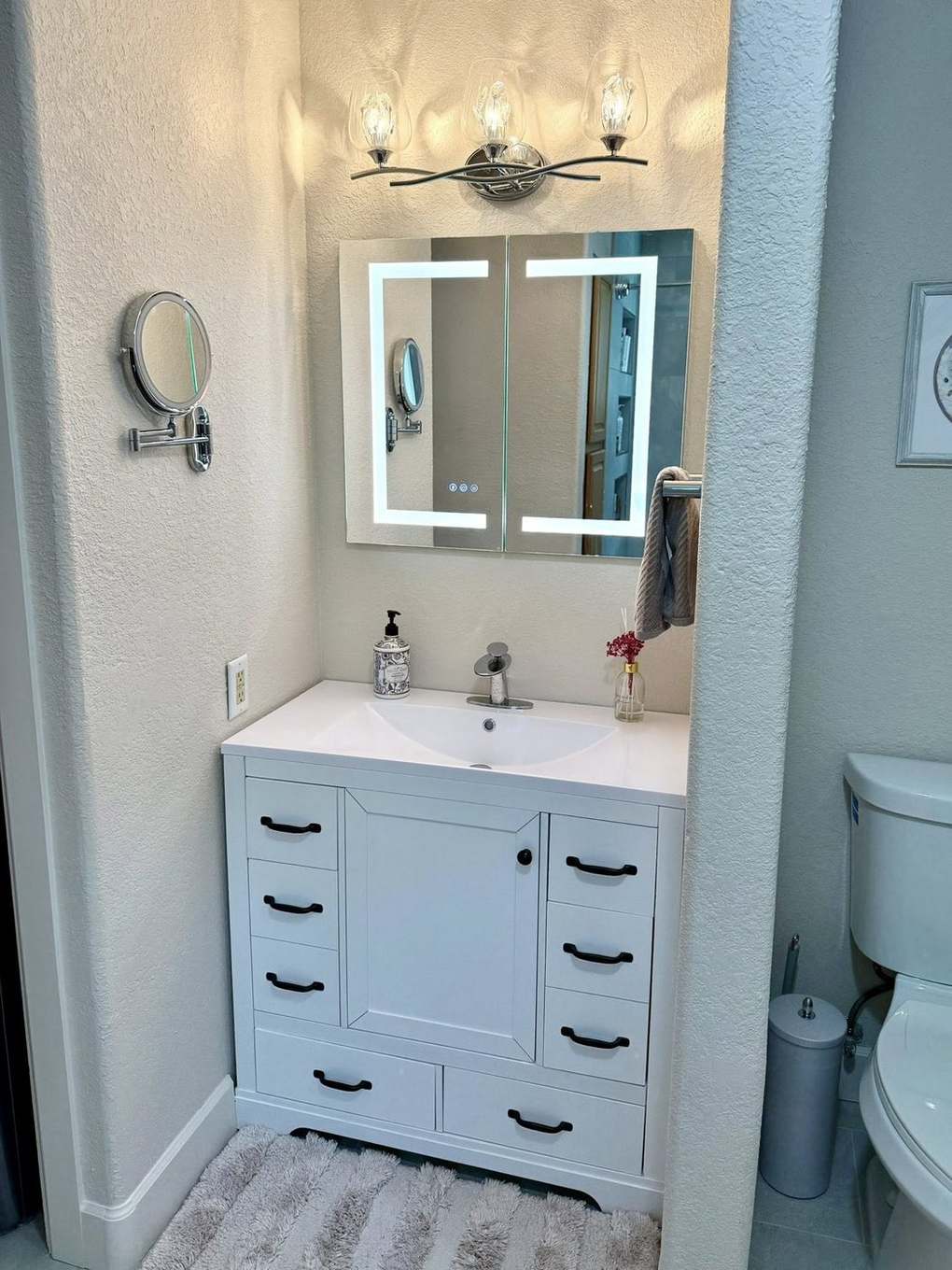 White vanity with LED mirror and modern sconce